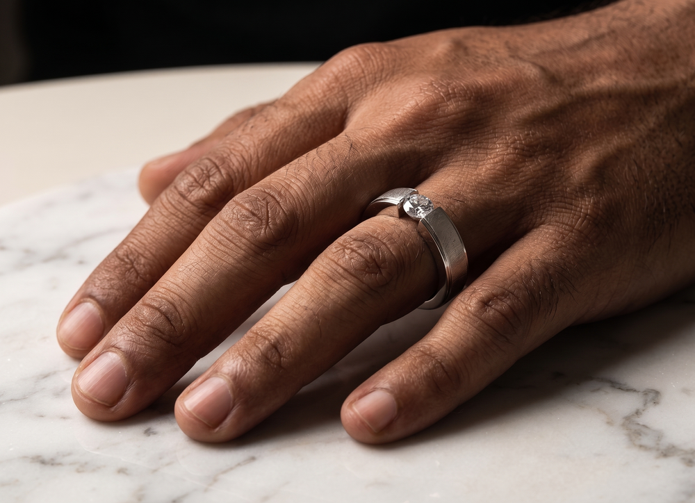Hand wearing a silver ring on a marble surface