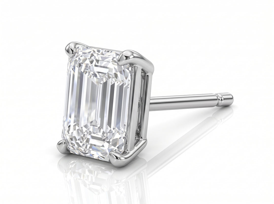 An emerald-cut diamond stud earring in a silver-colored metal setting, shown on a clean white background with a soft reflection underneath.
