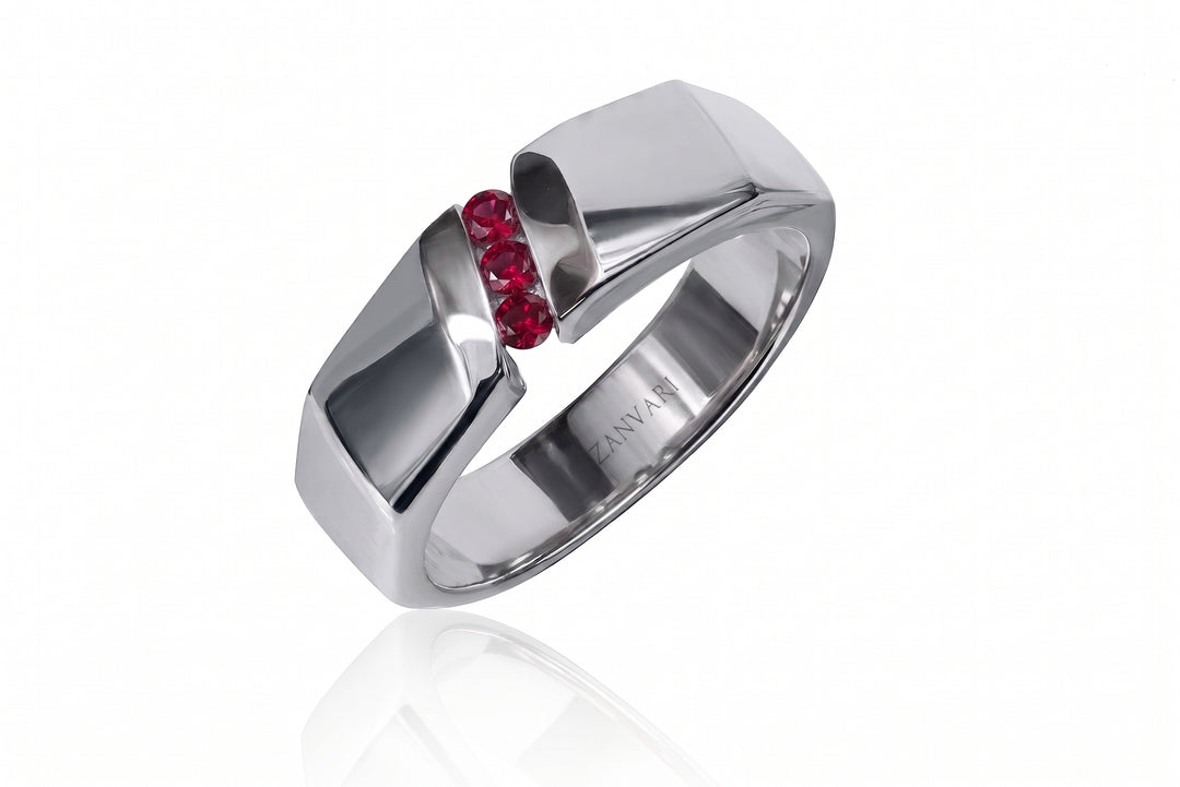 A modern silver-toned ring with a split geometric design and a row of small red gemstones at the center, shown on a clean white background with a soft reflection.