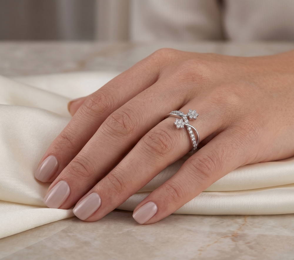Hand wearing a silver moissanite ring with floral design on a marble surface