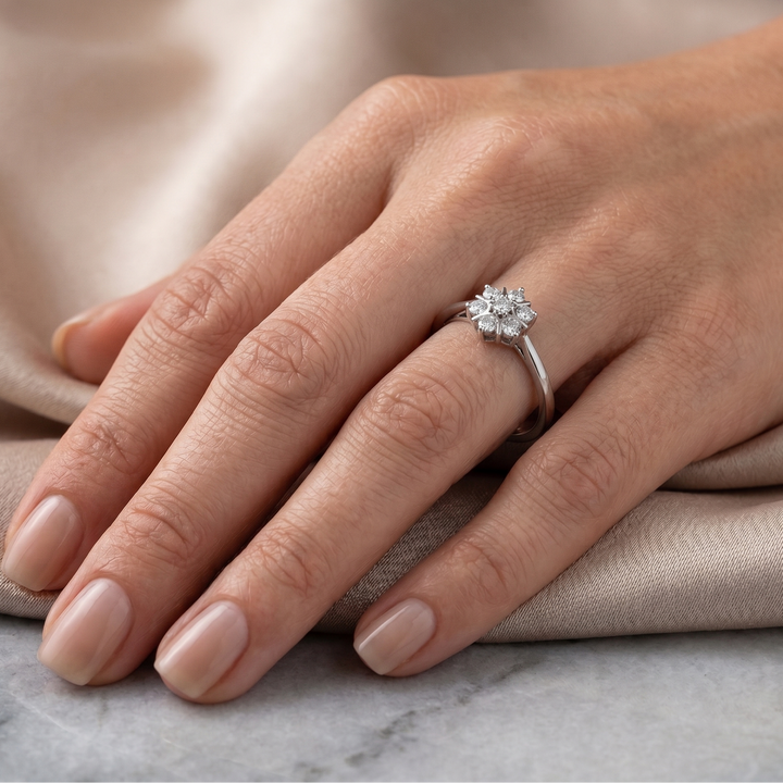 Hand wearing a floral moissanite ring on a neutral background