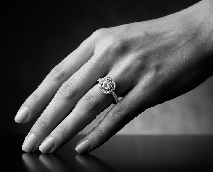 Close-up of a hand wearing a moissanite ring on a dark background