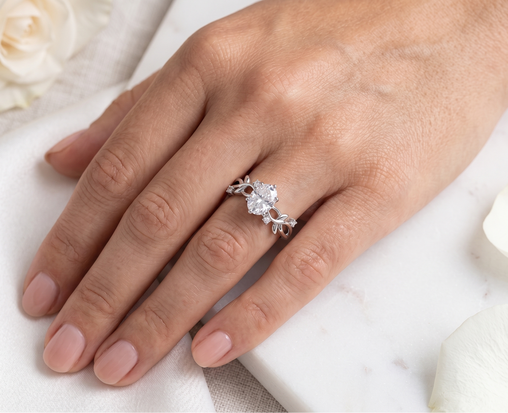 Hand wearing a silver ring with a oval cut moissanite on a white background