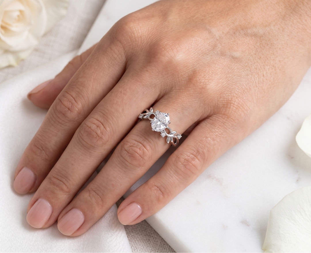 Hand wearing a silver ring with a oval cut moissanite on a white background