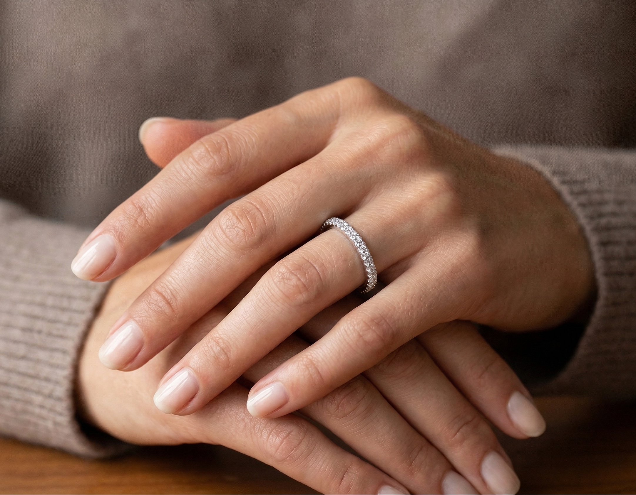 Close-up of hands with a ring on a neutral background