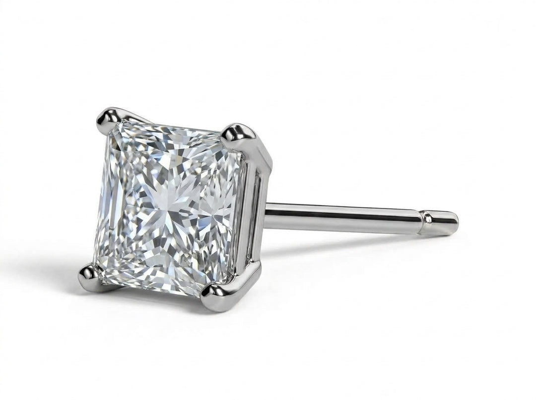 Close-up studio shot of a 1-carat princess-cut diamond stud earring mounted in a 4-prong white gold basket setting, viewed in profile against a clean white background.