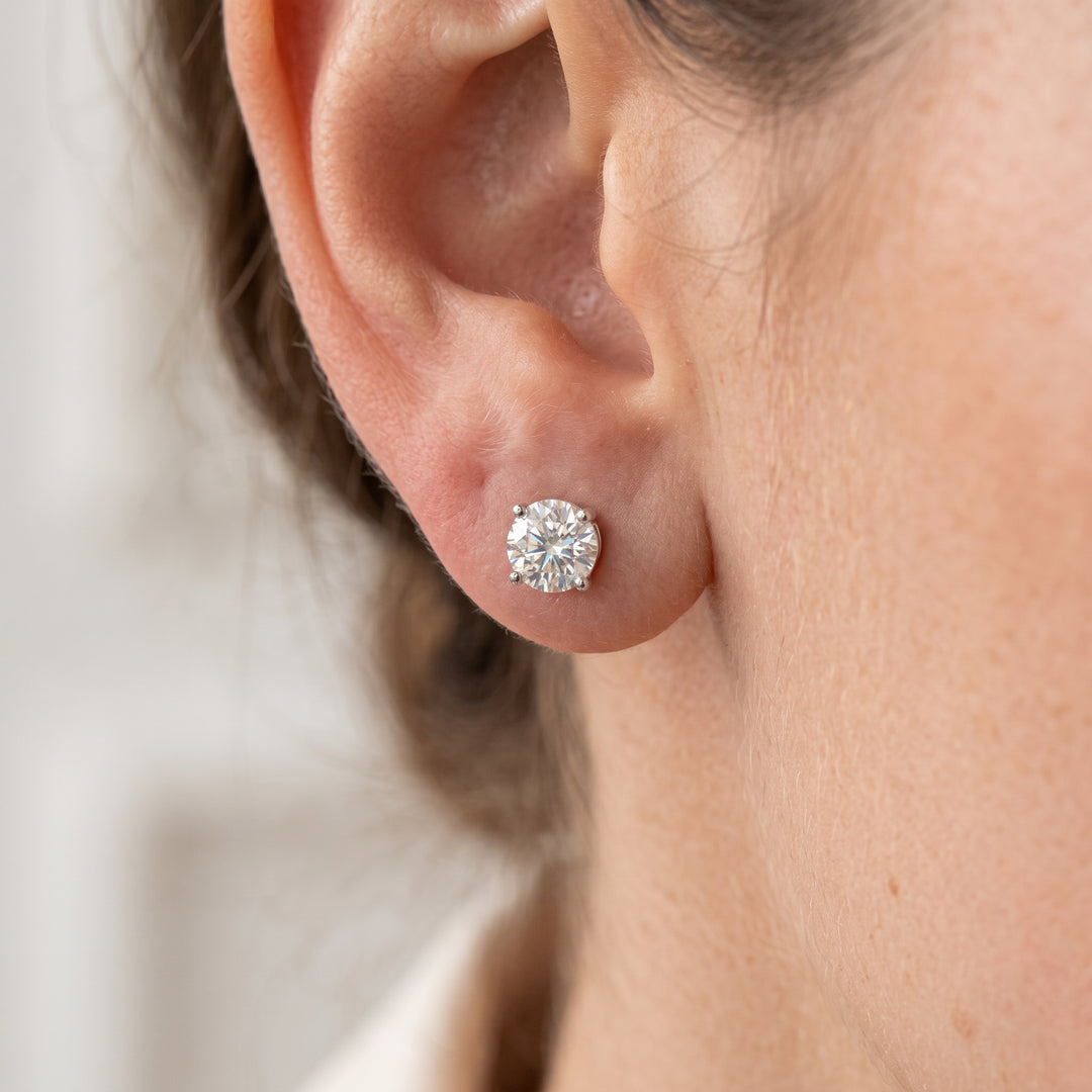 Close-up profile view of a woman wearing a round brilliant-cut lab diamond stud earring set in white gold on her earlobe.