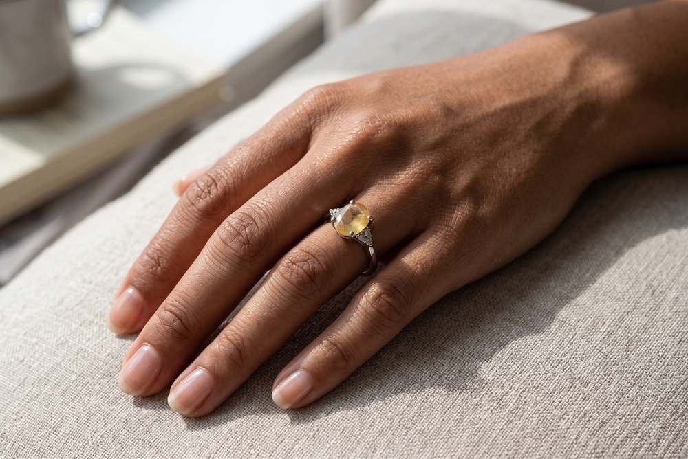 Yelloe sapphire ring worn by a model on a sofa