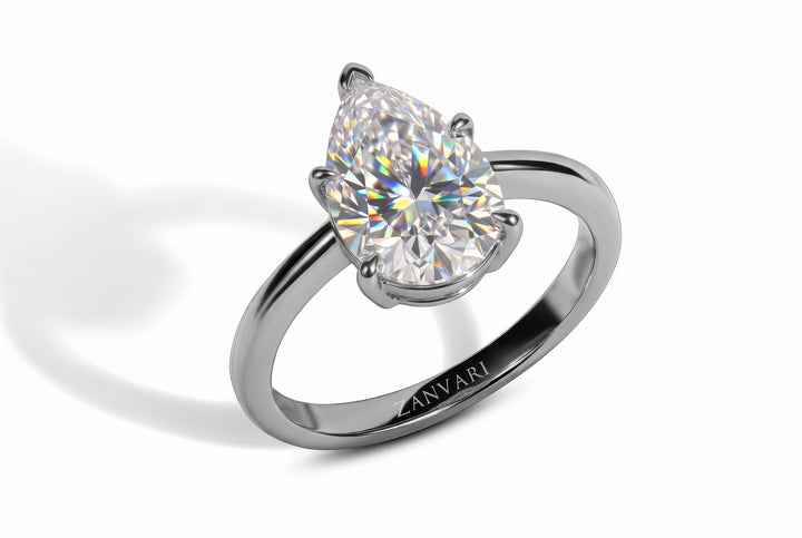 A pear-cut moissanite solitaire ring in a polished silver-colored metal band, featuring the engraved brand name 'ZANVARI' on the inner band, set against a clean white background with a soft shadow.