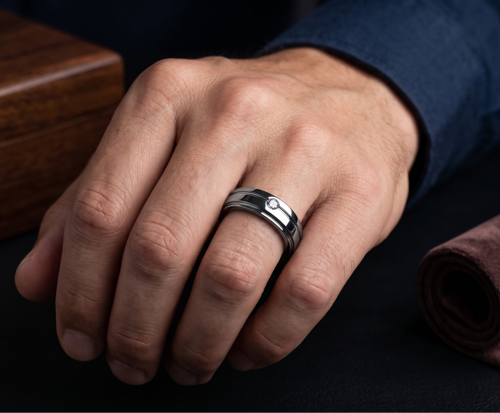 Hand wearing a silver engagement moissanite ring with a dark background