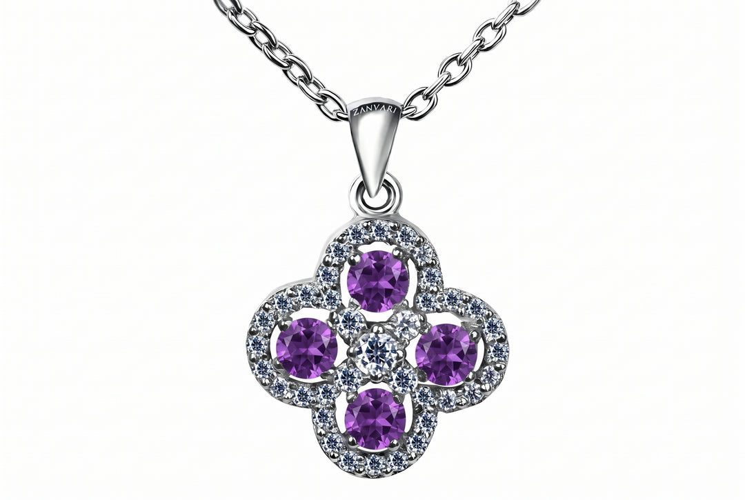 A silver-tone floral pendant necklace featuring four round purple gemstones surrounded by small clear stones, suspended from a silver chain on a white background.