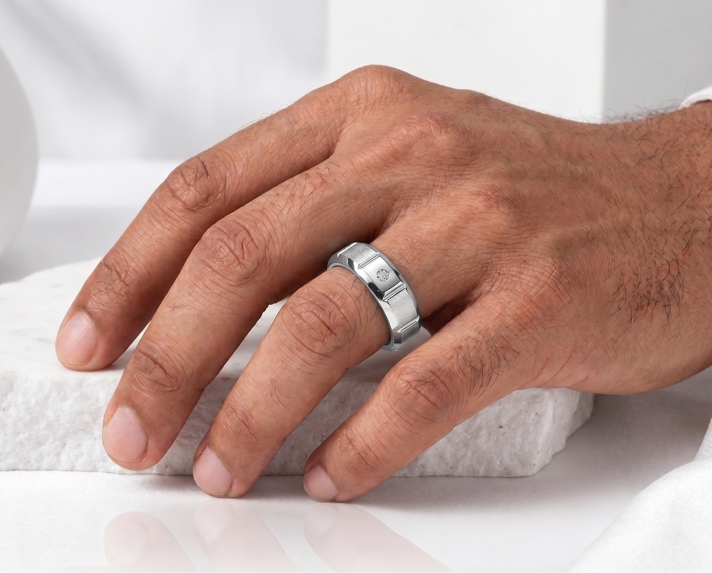 Hand wearing a silver diamond ring on a white background