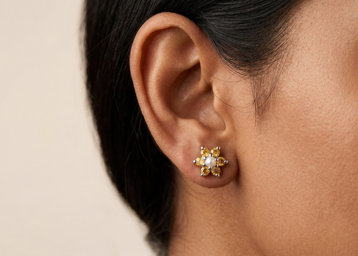 yellow sapphire earrings with a central pearl gemstone worn by a person against a neutral background