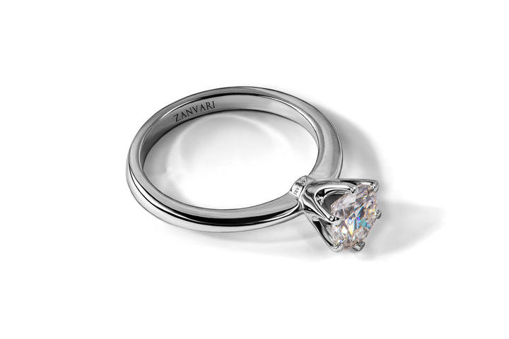 A silver ring with a large, sparkling solitaire Moissanite stone set in a four-prong setting, engraved with the word "ZANVARI" inside the band.
